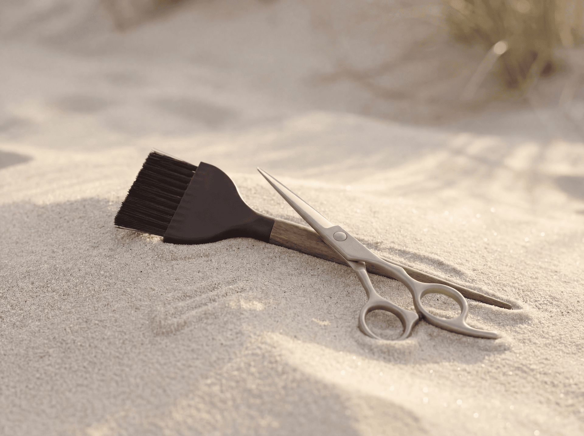 Colour brush and scissors resting on sand